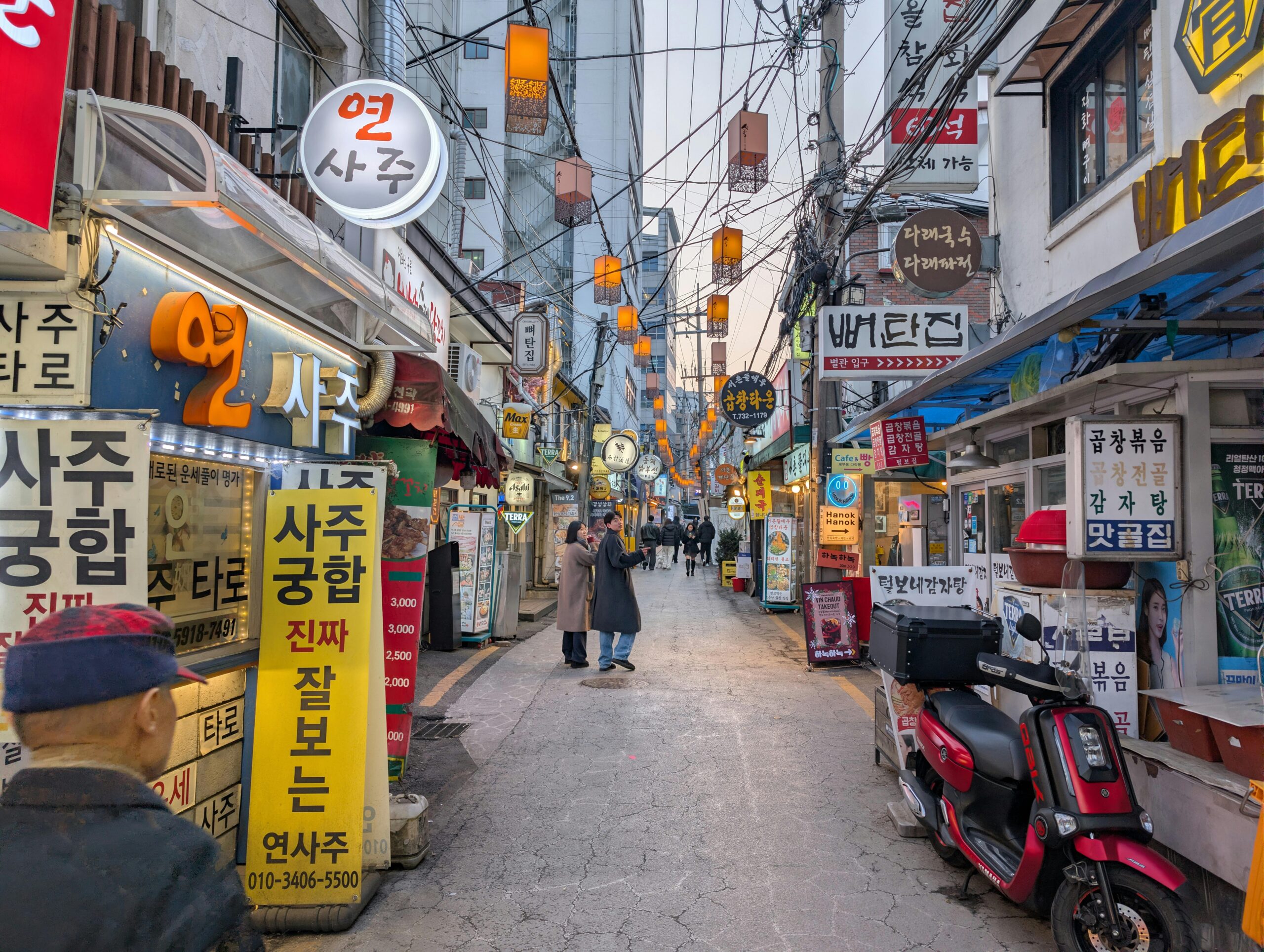 Bustling evening street in Seoul with traditional signage, people, and warm lighting.